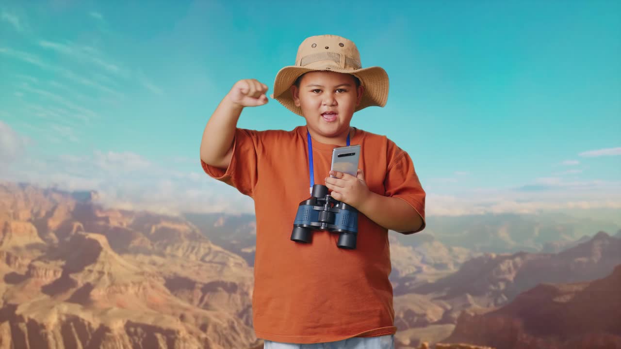 Asian Boy With A Hat And Binoculars Looking At Smartphone Then Screaming Goal Celebrating While Traveling At The Top Of Mountain. Boy Researcher Examines Something, Travel Tourism Adventure Concept