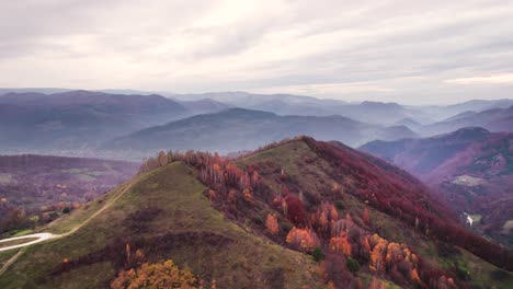 panorama aéreo de la cresta de la colina verde con la cordillera en el fondo, dumesti, transilvania