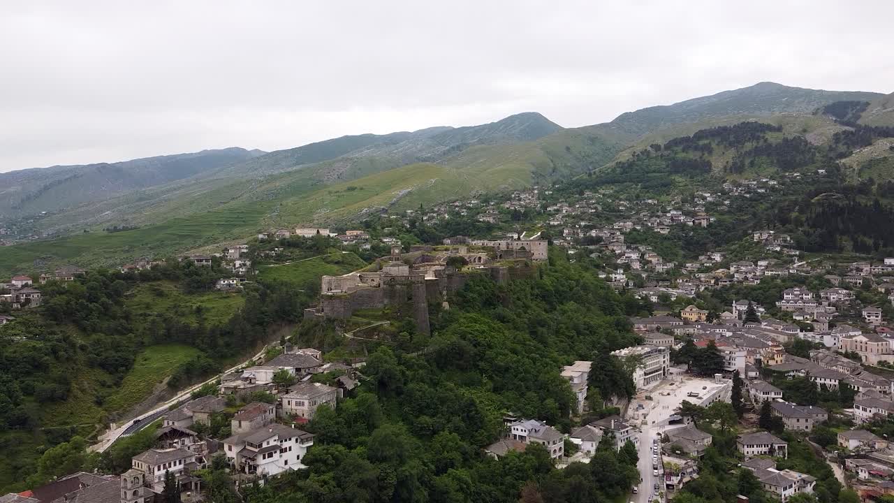 vista aérea del castillo de gjirokastra en albania, rodeado de exuberantes colinas verdes y edificios históricos de la ciudad ubicados en el valle