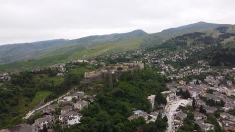 Vista-Aérea-Del-Castillo-De-Gjirokastra-En-Albania,-Rodeado-De-Exuberantes-Colinas-Verdes-Y-Edificios-Históricos-Ubicados-En-El-Valle.