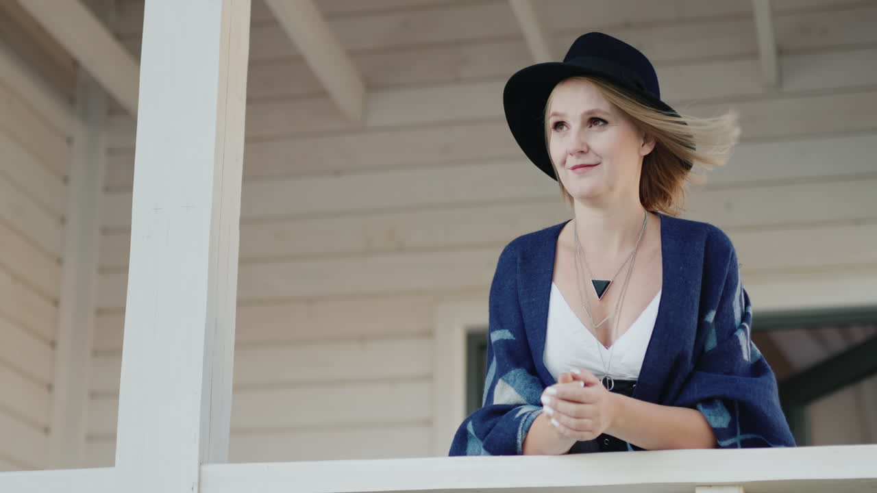 집 테라스에서 모자를 쓴 세련된 여성 1