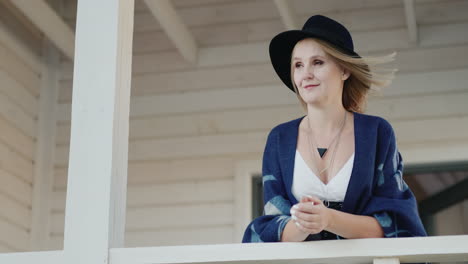 stylish woman in a hat on the terrace of her home 1