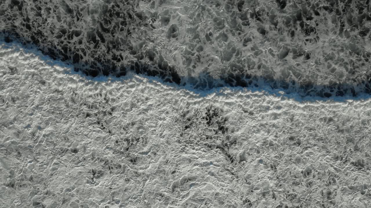 Drone overview of powerful ocean waves in Siargao, Philippines, with white foam splashing against the shoreline, natural textured water backdrop