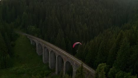flying a powered paraglider over a bridge. chmarocsky viaduct in slovakia, europe. following a pilot with a drone.