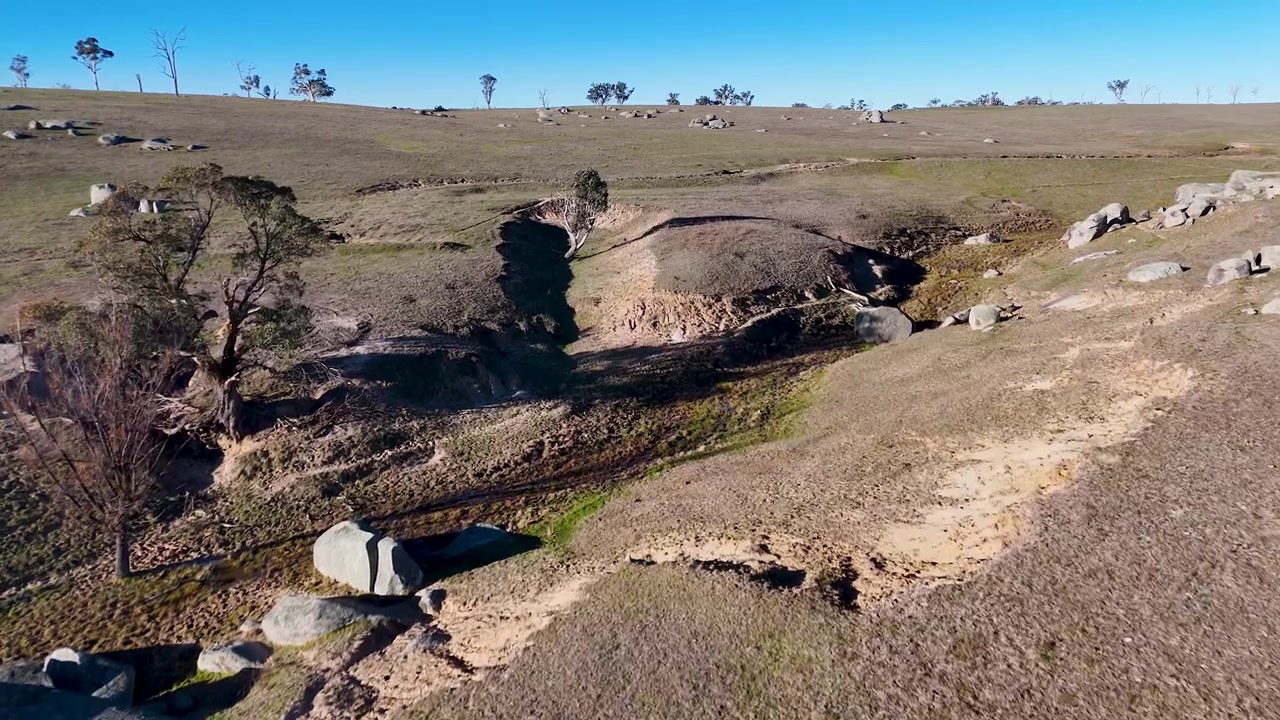 Vue par drone survolant un terrain rocheux et des champs secs à Uralla, Nouvelle-Galles du Sud, Australie.