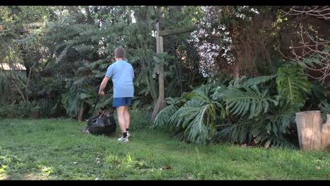 Hombre-Cortando-El-Césped-En-Un-Jardín-Yendo-Hacia-Atrás-Y-Hacia-Adelante-Imágenes-De-4k