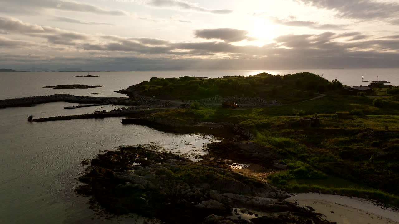 Aerial view of the serene coastline at Skrolsvik on Senja Island in Northern Norway, showing calm waters, rocky shores, and soft evening sunlight reflecting on the peaceful beach