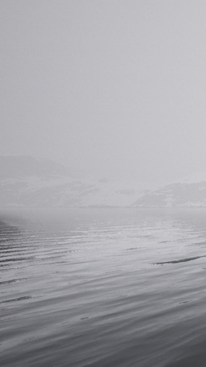 Snow covers the ground and mountains under a cloudy sky near a remote location