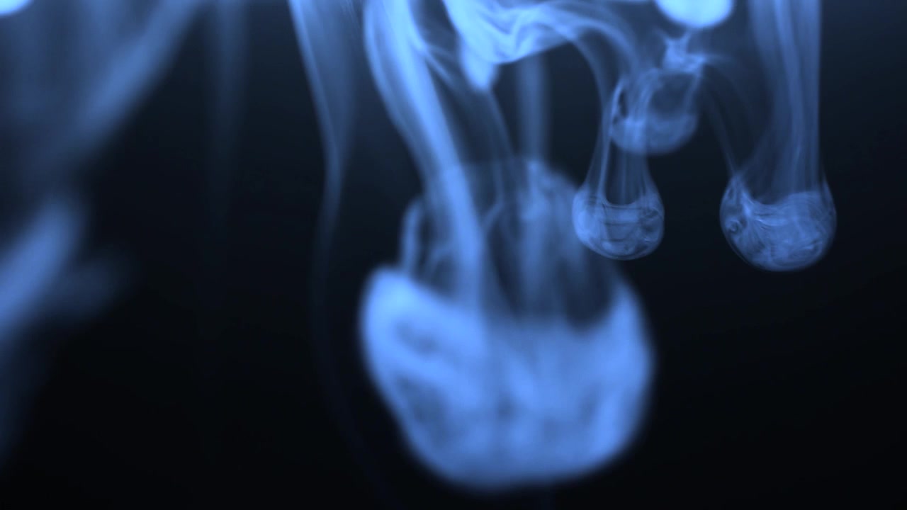 Fumo blu vorticoso in un ambiente scuro.