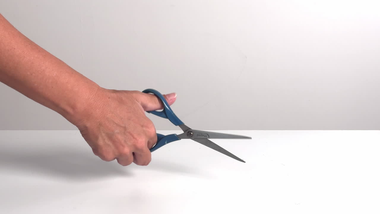 Primo piano di una mano che apre e chiude delle forbici blu
