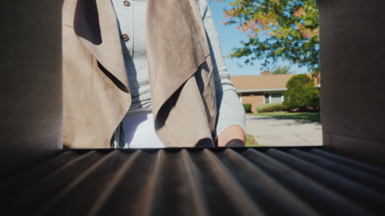 A Young Woman With A Small Dog In Her Arms Picks Up Letters From A Mailbox