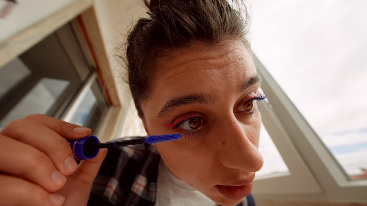 Young Woman Applying Blue Mascara to Her Eyelashes
