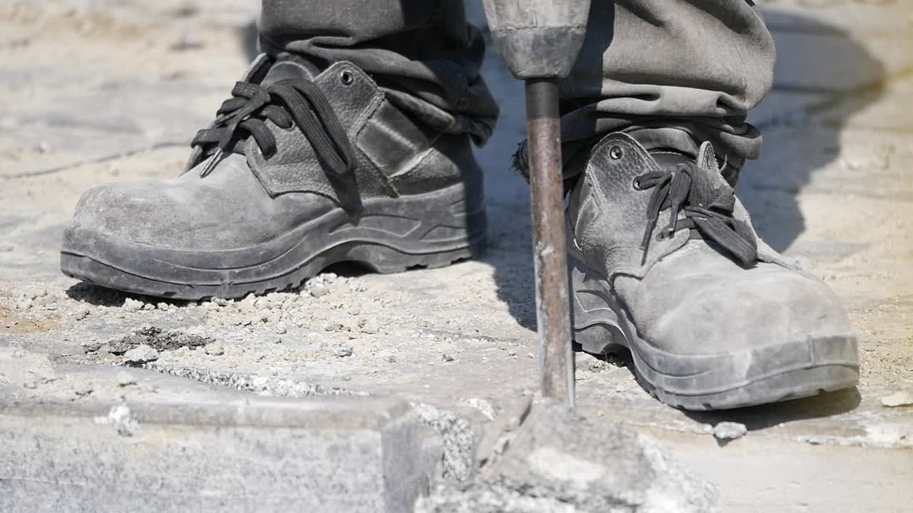 Worker using a jackhammer to break up pavement