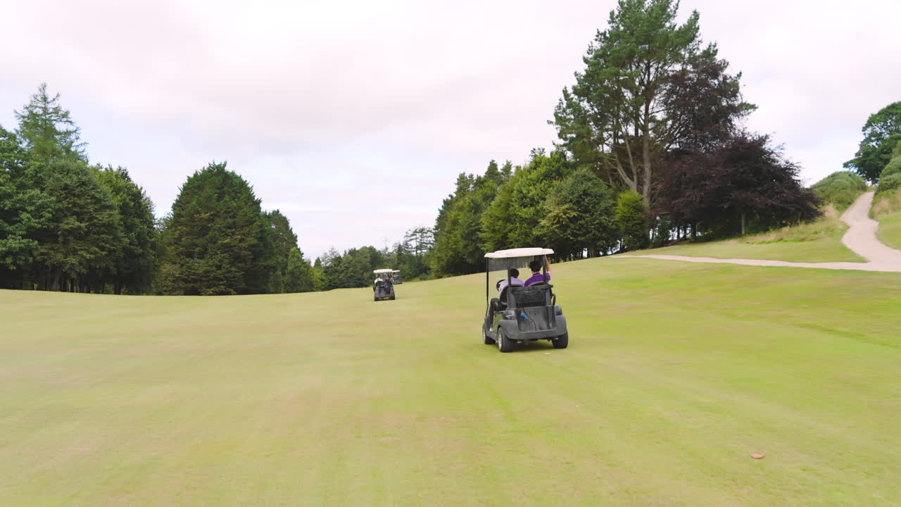 Male golf players driving golf cart with another golf cart on golf course, copy space