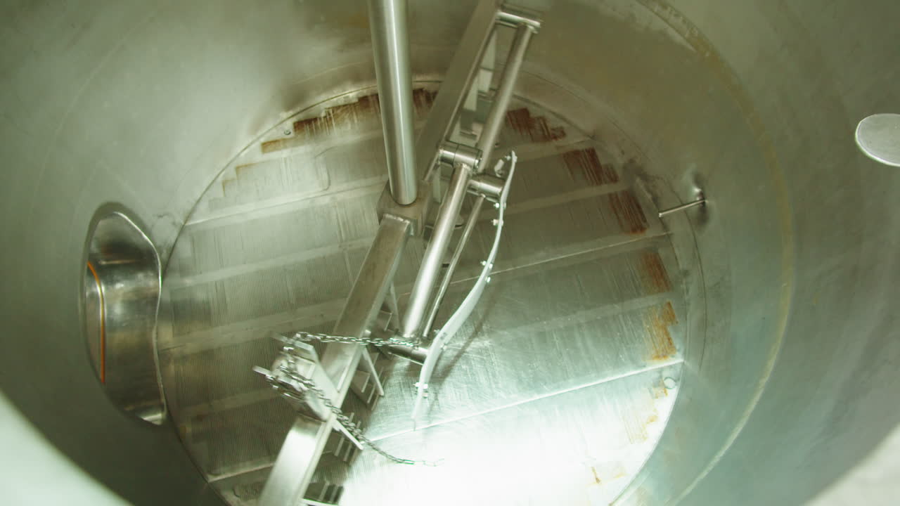 Craft beer production factory, brewery manufacture. Putting barley malt grains in conveyor close-up. Brewing, cooking alcohol in metal vats bottles