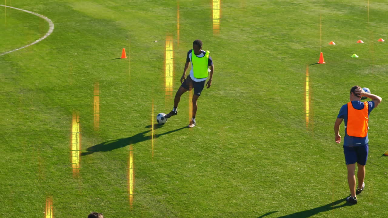 Controlling ball on grassy field, soccer player in yellow vest with orange cones