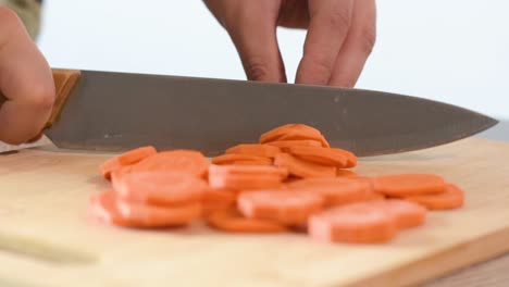 primer plano de la mano de una mujer cortando una zanahoria.