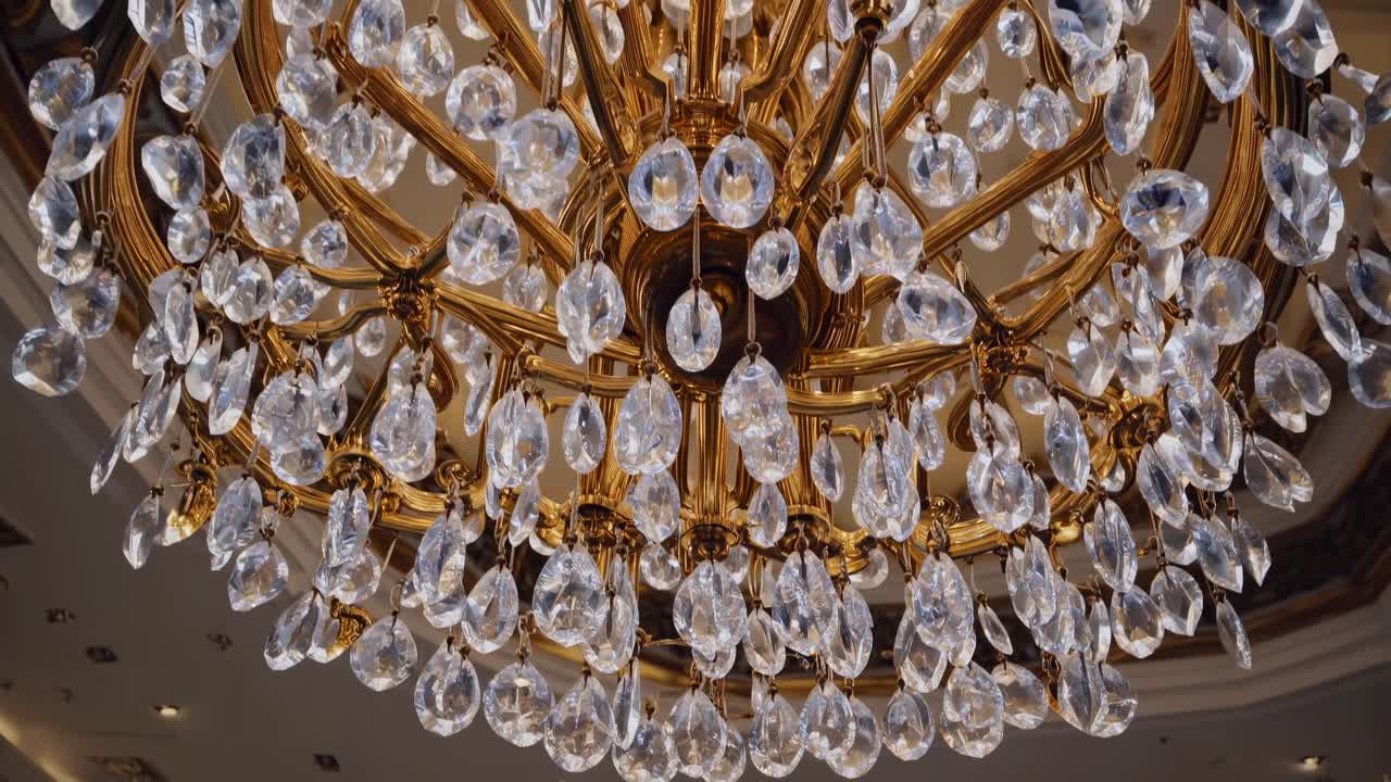 Ornate golden chandelier hanging with sparkling crystal elements, casting luxurious light across refined hotel interior, radiating sophisticated elegance and glamorous ambiance