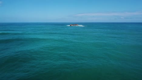 Drone-Shot-flying-towards-an-isolated,-small,-rocky-island-located-far-off-of-the-coast-of-Oahu,-Hawaii