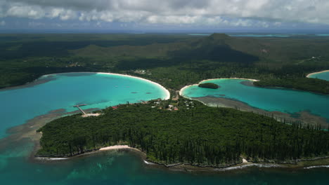 The-narrow-land-bridge-and-peninsula-on-the-Isle-of-Pines-between-Kuto-Bay-and-Kanumera-Bay-called-Presqu’île-de-Kuto---pull-back-aerial-reveal