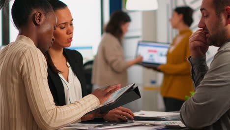 close up of diverse business team checking graphs from tablet making new strategy.