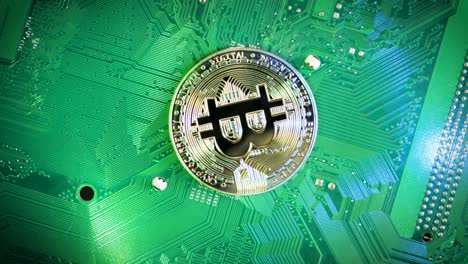 Vista-De-Arriba-Hacia-Abajo-Girando-Bitcoin-De-Oro-En-La-Placa-De-Computadora-Verde,-Ingresos-Pasivos-Al-Minar-Bitcoin