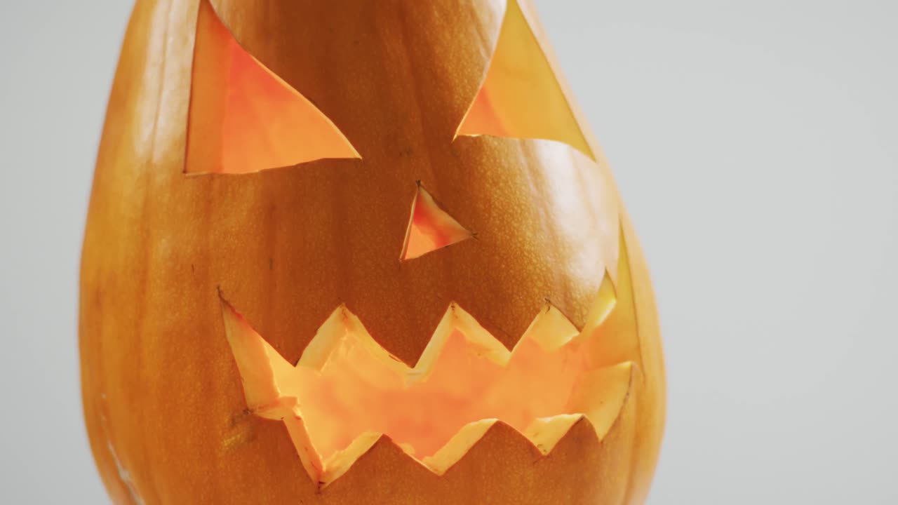 vista de cerca de la cara aterradora tallada calabaza de halloween contra un fondo gris