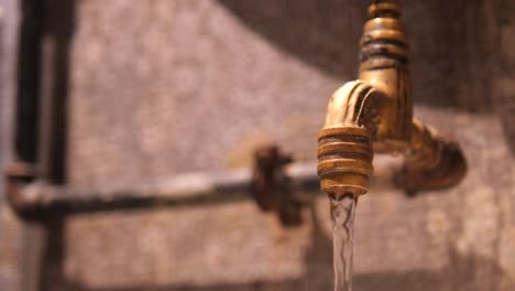 close-up of an old brass faucet with running water