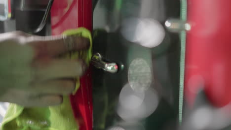 close-up of hand wiping shiny chrome handle on red coffee machine with green cloth, focusing on cleaning and maintaining the appliance, ensuring it looks spotless and polished