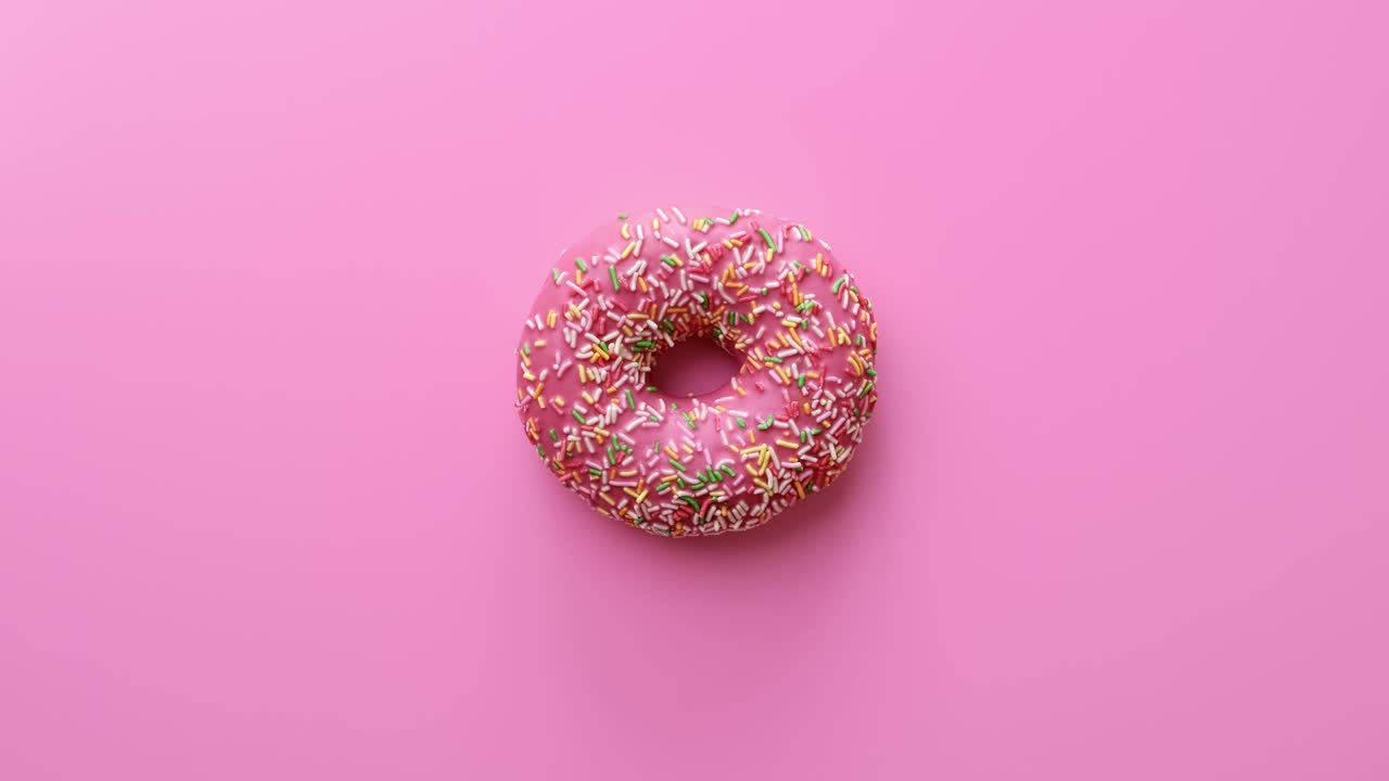 Rosquinha frita doce caseira saborosa pronta para o lanche, girando isolada em rosa