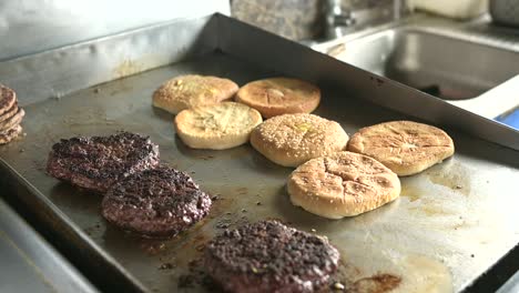 cocinero de cultivos preparando bollos para hamburguesas en superficie caliente