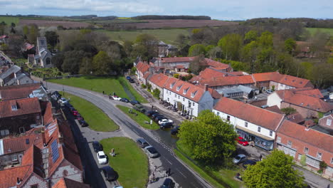 rising establishing aerial drone shot of beautiful old english village burnham market on sunny and cloudy day in north norfolk with trees and fields in background