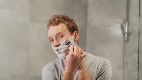 handsome young guy shaves his beard with a razor