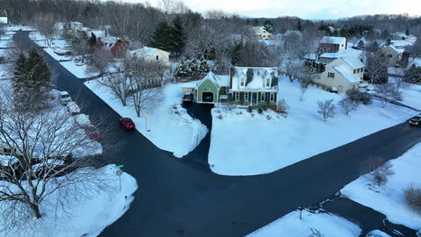 green cape cod home covered in winter snow