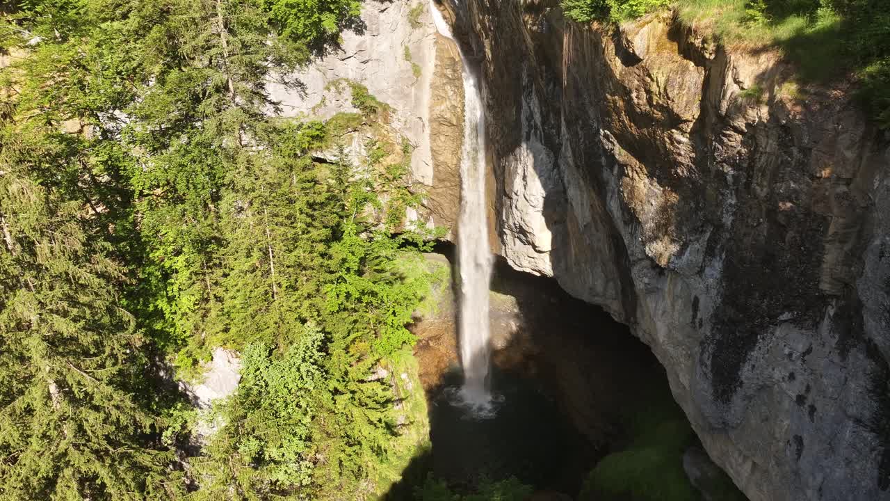 Tschessibachfall waterfall plunging in a narrow vertical stream between forested slopes and rocky cliffs. Glarus Süd, Switzerland