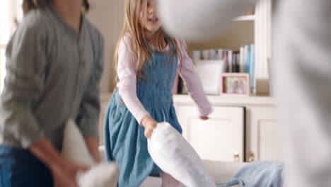 happy family having pillow fight mother and father enjoying playing with children at home having fun together on weekend