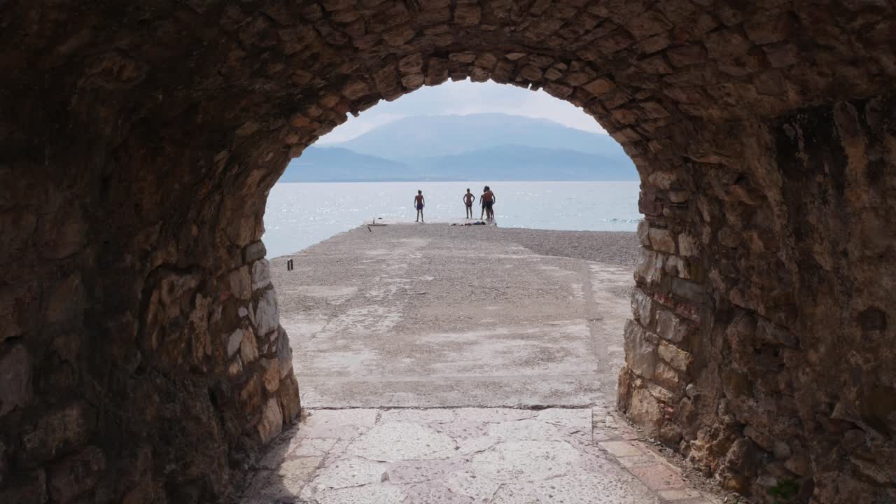 Children jumping to the sea, seen through the ramparts of the old port
