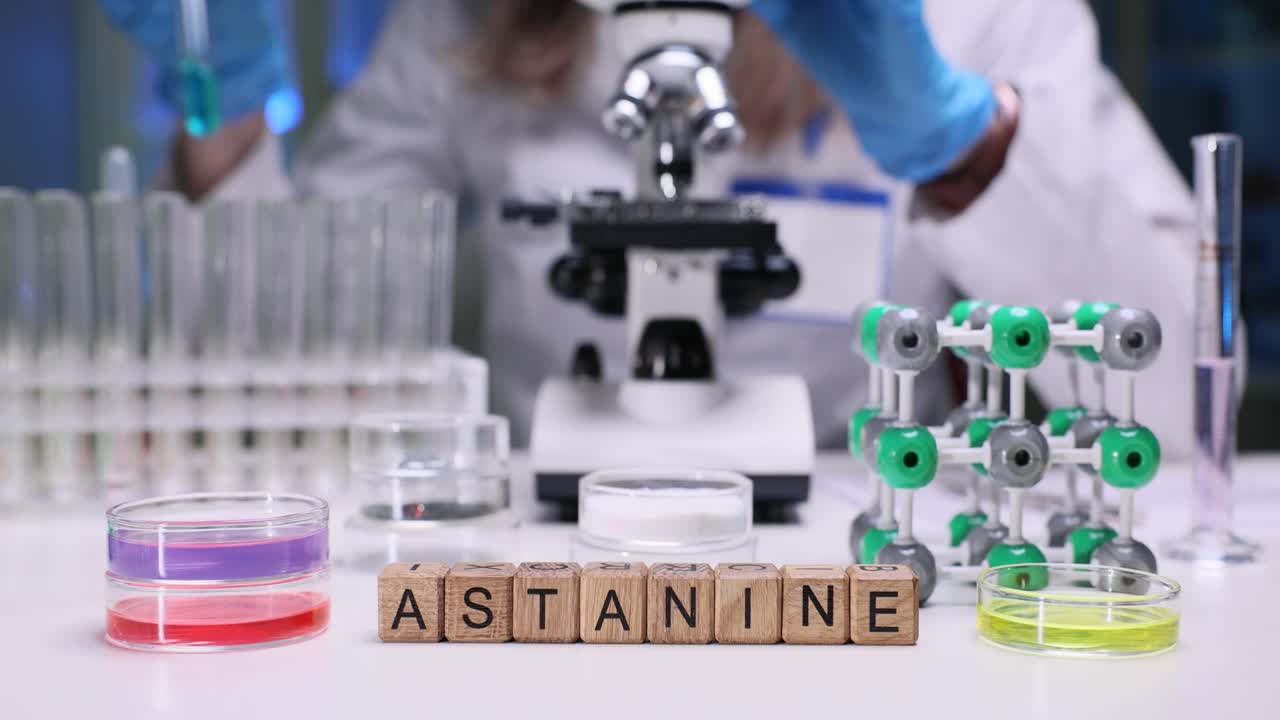 Blocchi con la parola Astato su un tavolo da laboratorio con uno scienziato sullo sfondo
