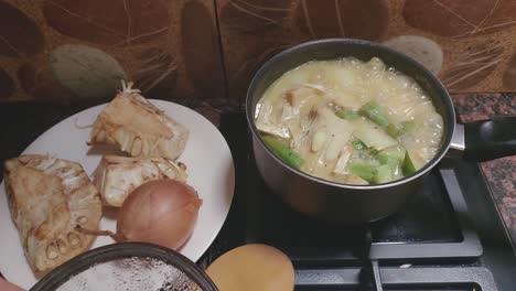 Overhead-pov-of-opening-a-lid-and-stirring-a-pot-of-ginataang-langka-or-traditional-filipino-unripe-jackfruit-stew-showing-the-local-delicacy,-culture-and-candid-daily-home-life-in-the-Philippines