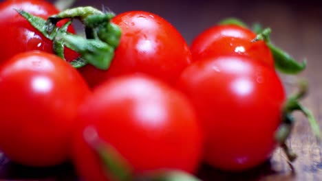 tomates cherry mojados jugosos rojos diminutos frescos crudos en la superficie de la cocina de madera enfoque selectivo dolly izquierda cerrar