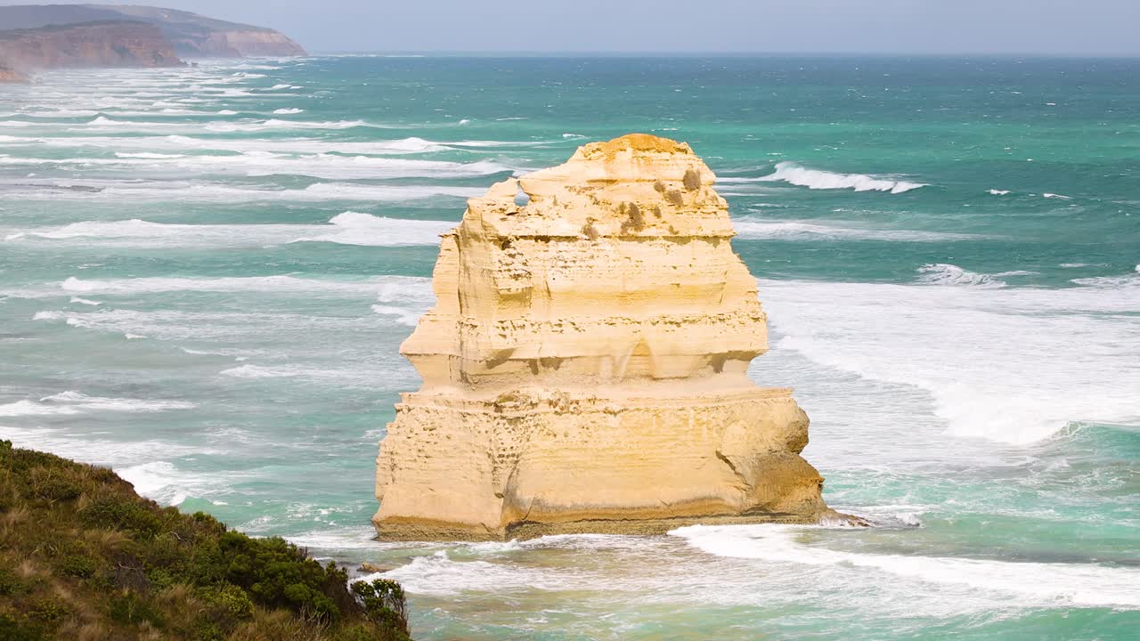 A serene view of the Twelve Apostles with waves crashing against the limestone formations under clear skies