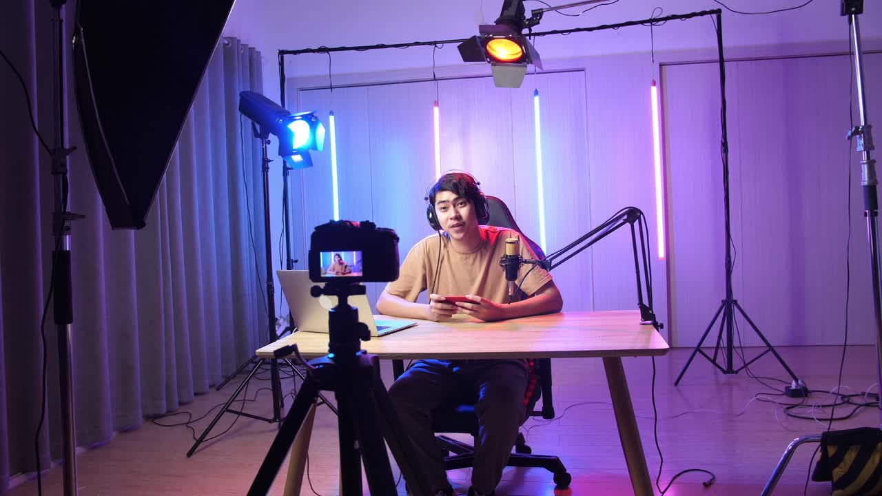 Asian Man Holding Mobile Phone And Talking To Camera While Live Stream, Professional Light Equipment