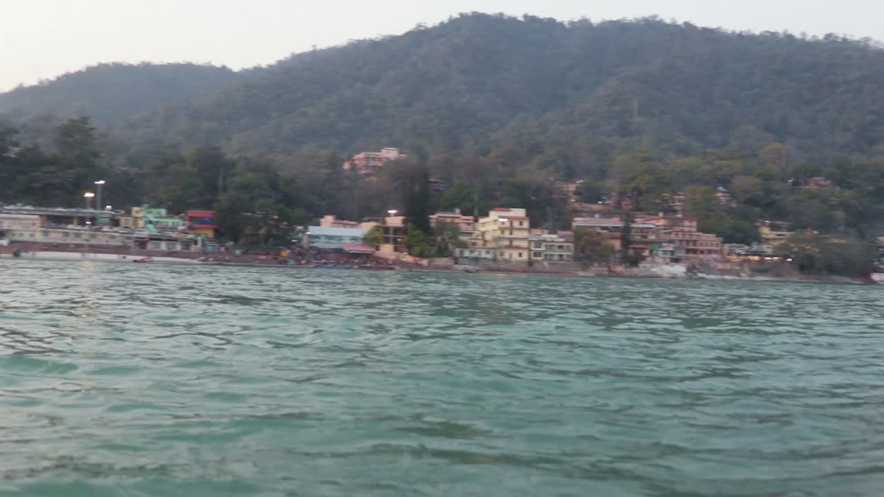 niño aislado sentado y rezando en la orilla del río ganges desde un ángulo plano