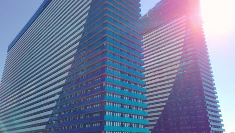 shot of reflections of sun, clouds and sky on glass windows of city skyscraper.