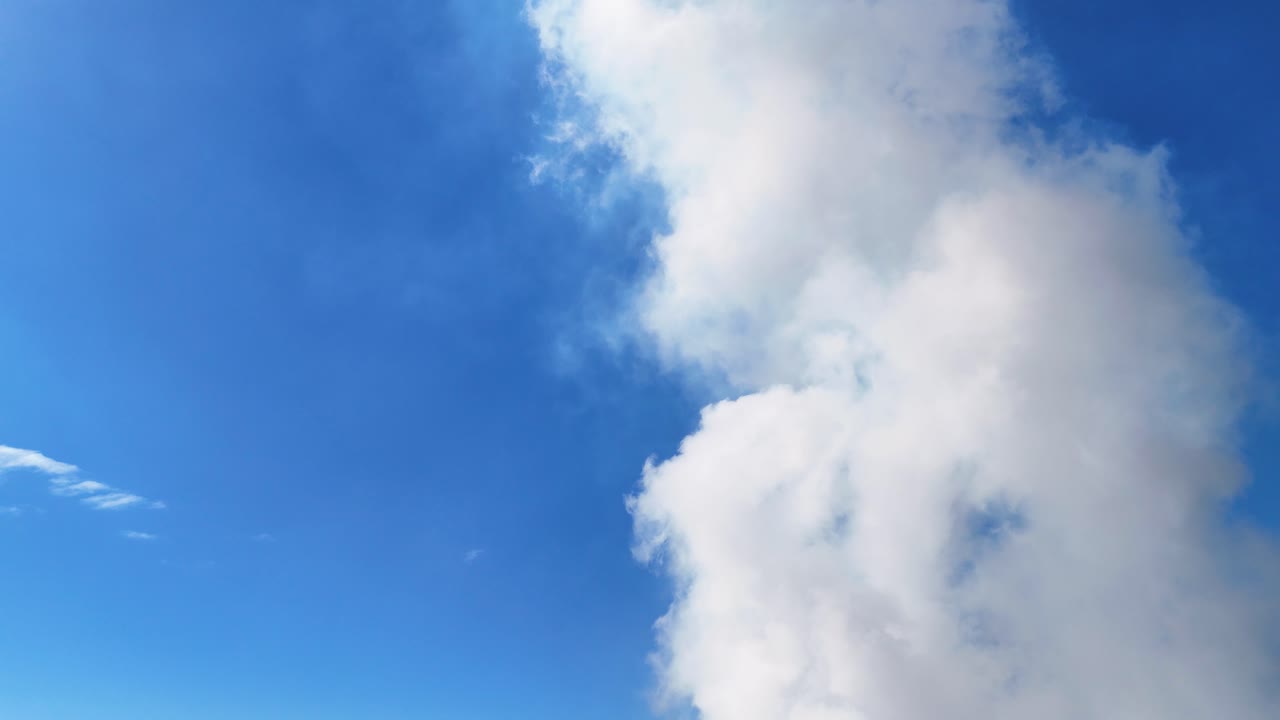 White clouds drift across a vibrant blue sky, creating a dynamic and serene atmosphere with natural lighting