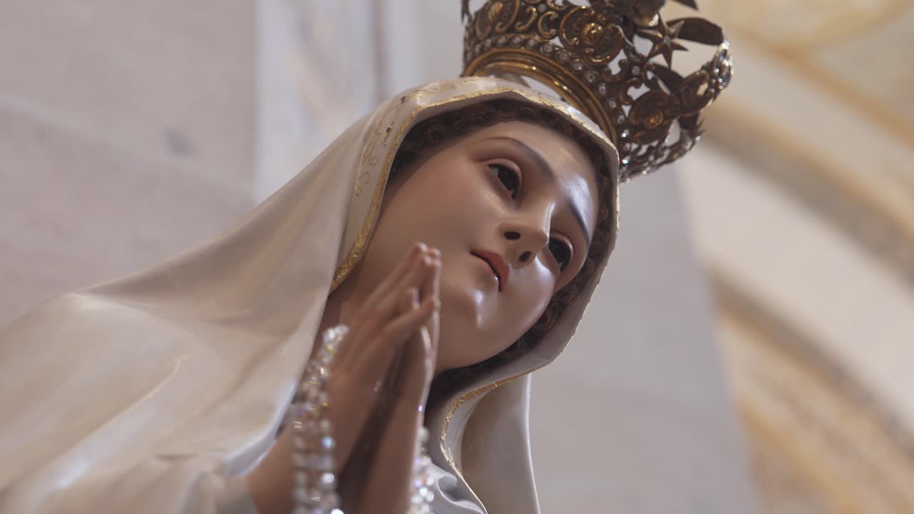 Primo piano della statua della Vergine Maria Nostra Signora di Fatima che tiene il rosario in preghiera.