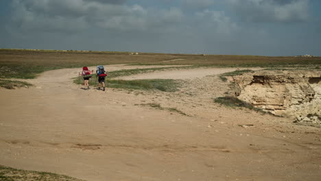 excursionistas en un camino polvoriento a lo largo de un acantilado
