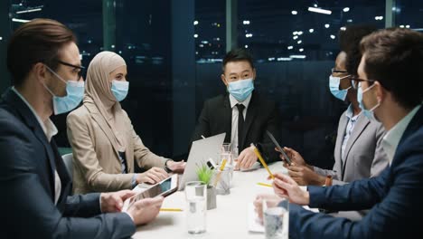 현대 사무실에서 열린 팀 회의에서 의료용 마스크를 쓴 다민족 기업인 그룹과 프로젝트 2에 대해 토론
