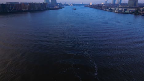 revealing aerial shot over north sea canal in amsterdam with a tanker ship coming, twilight