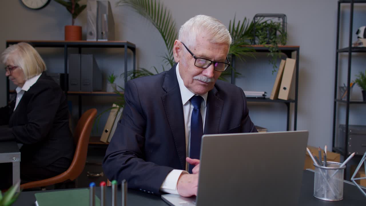 direttore aziendale senior che lavora al portatile alla scrivania, balla, celebra la vittoria, ottiene un buon risultato